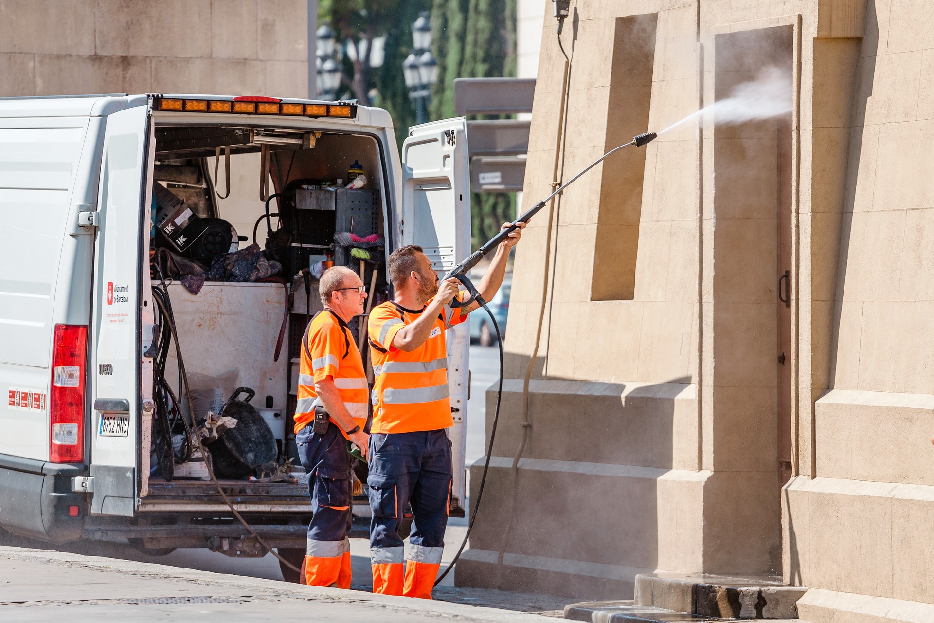 Public service worker washing historical building using water jet